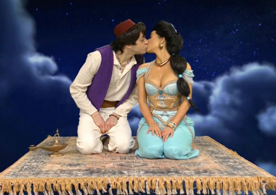 Kim Kardashian and Pete Davidson dressed as Aladdin and Jasmine kissing on a magic carpet.