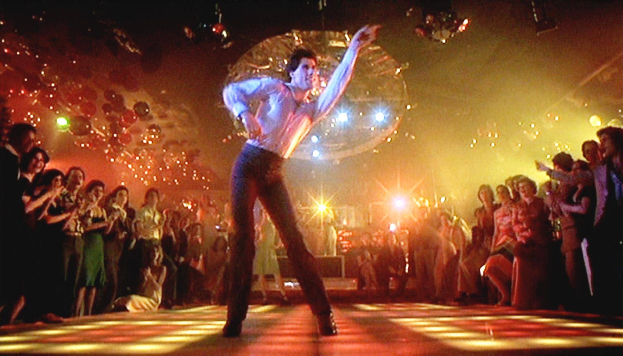 A man dances on a lighted stage in a nightclub in "Saturday Night Fever."