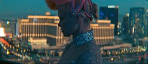 A woman in a glitzy costume and headdress with the lights of Las Vegas in the background