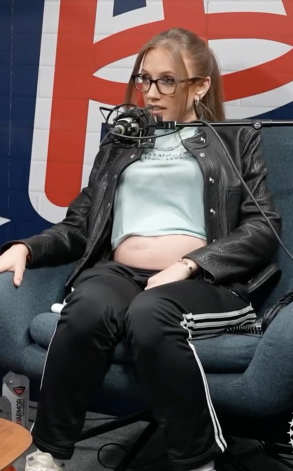 Kat Timpf seated, wearing glasses and a leather jacket, discussing online abuse during pregnancy.