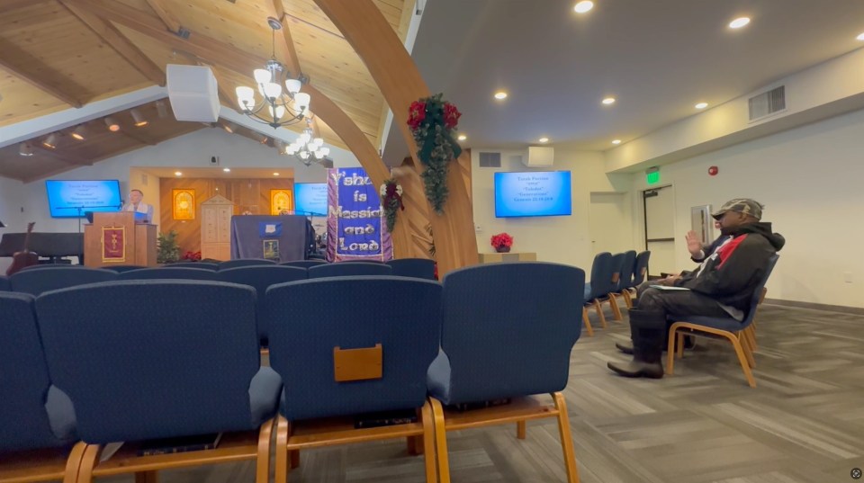 Interior of a church sanctuary with a person sitting in a pew.