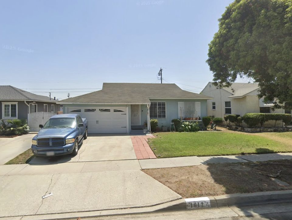 Photo of a light blue house with a two-car garage and a blue pickup truck parked in the driveway.