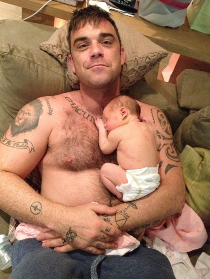 Robbie Williams holding his newborn daughter.