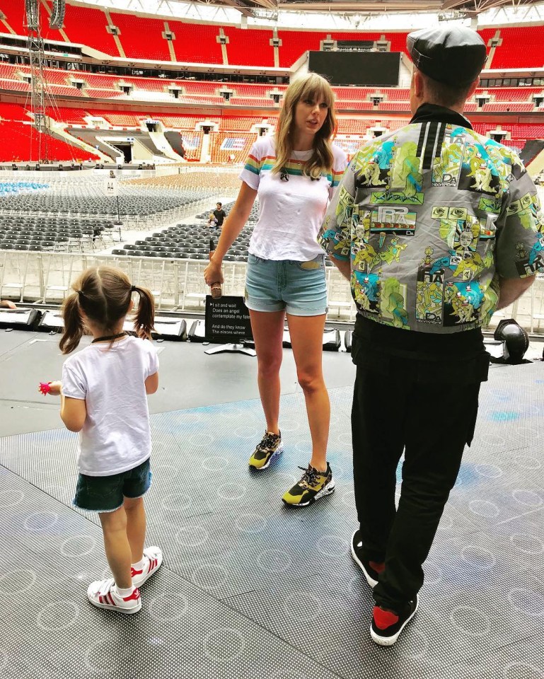 A woman and a man stand on a stage in a stadium with a young girl.