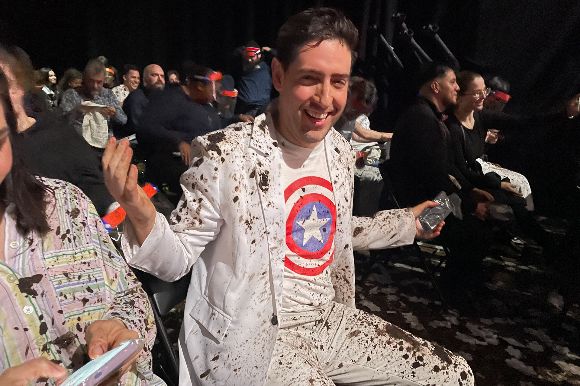 A photo of an attendee at the Captain America: Brave New World “Collateral Stain Screening” wearing a white suit and Captain America T-shirt displaying the aftermath of the event