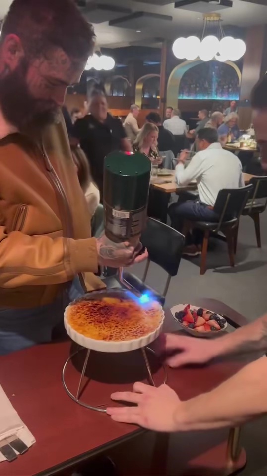 A man flambés a crème brûlée in a restaurant.