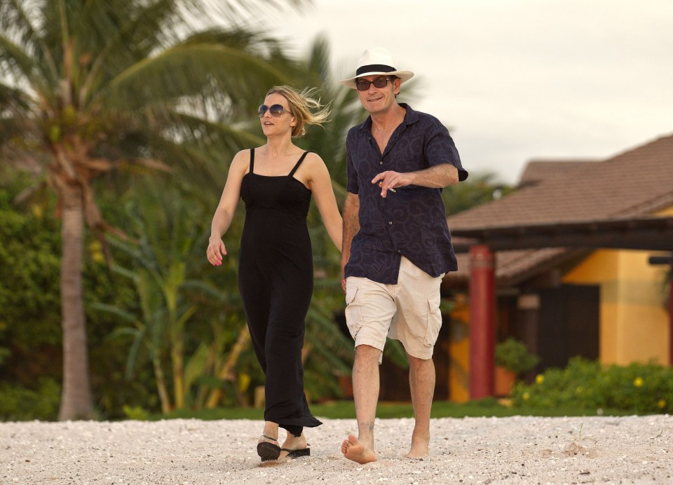 Charlie Sheen and Brooke Mueller walking on a beach.