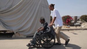 A man pushes a person in a wheelchair.