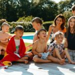 A family posing outside in swimsuits near a pool.