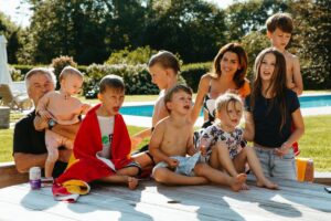 A family posing outside in swimsuits near a pool.