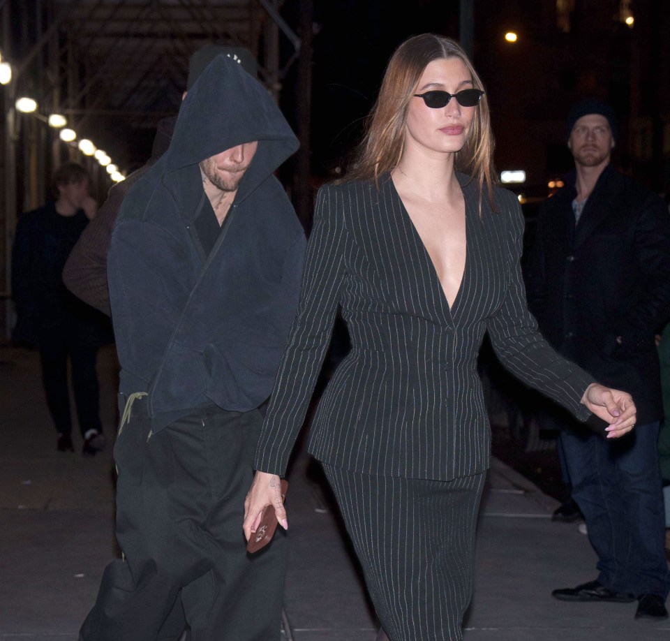 Justin Bieber and Hailey Bieber walking together at night.