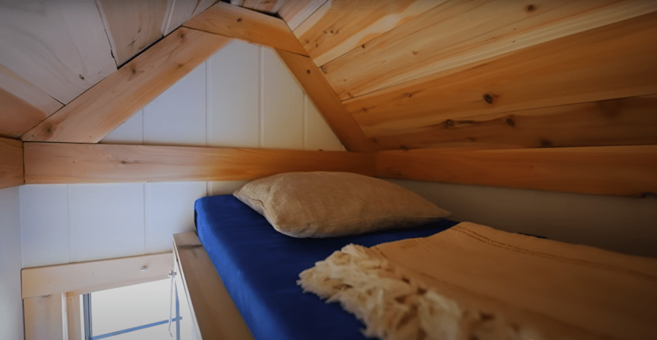 Loft bed with blue bedding and tan pillow.