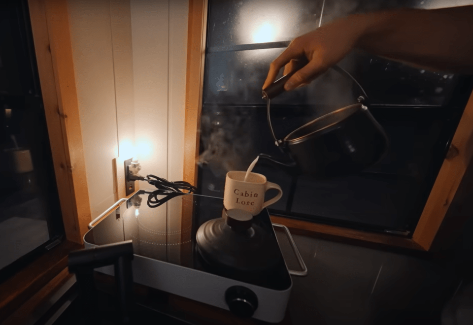 Pouring hot water from a kettle into a mug.