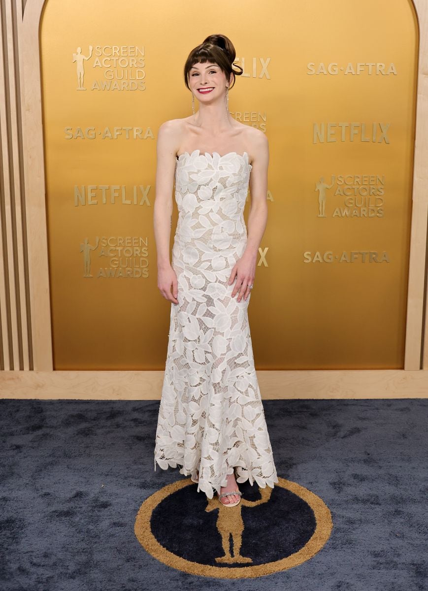 Dylan Mulvaney wearing a strapless white Simkhai floral lace gown and heels on the SAG Awards 2025 red carpet.