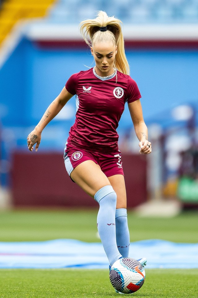 a female soccer player wearing a maroon shirt and shorts kicks the ball