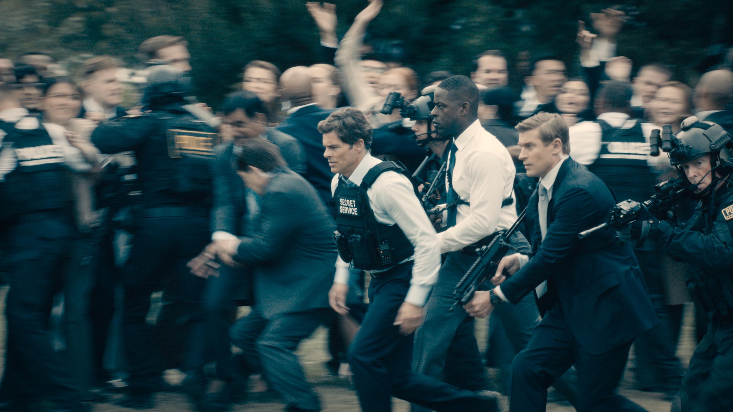 Xavier and other secret service agents rush the president around a crowd of angry Americans in Paradise