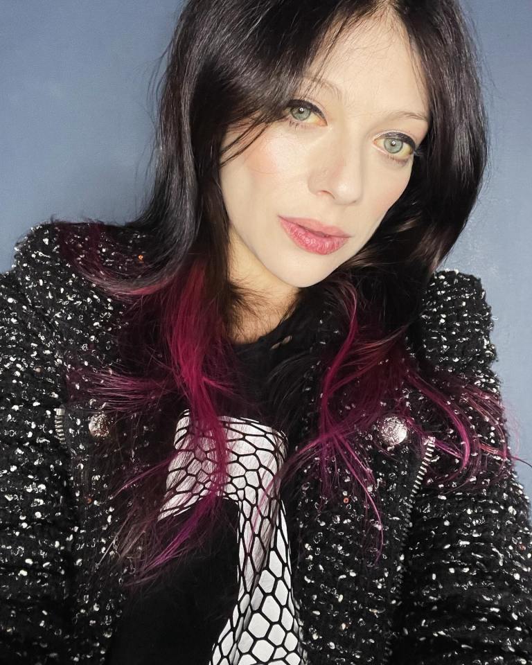 Michelle Trachtenberg in a black jacket with pink highlights in her hair.