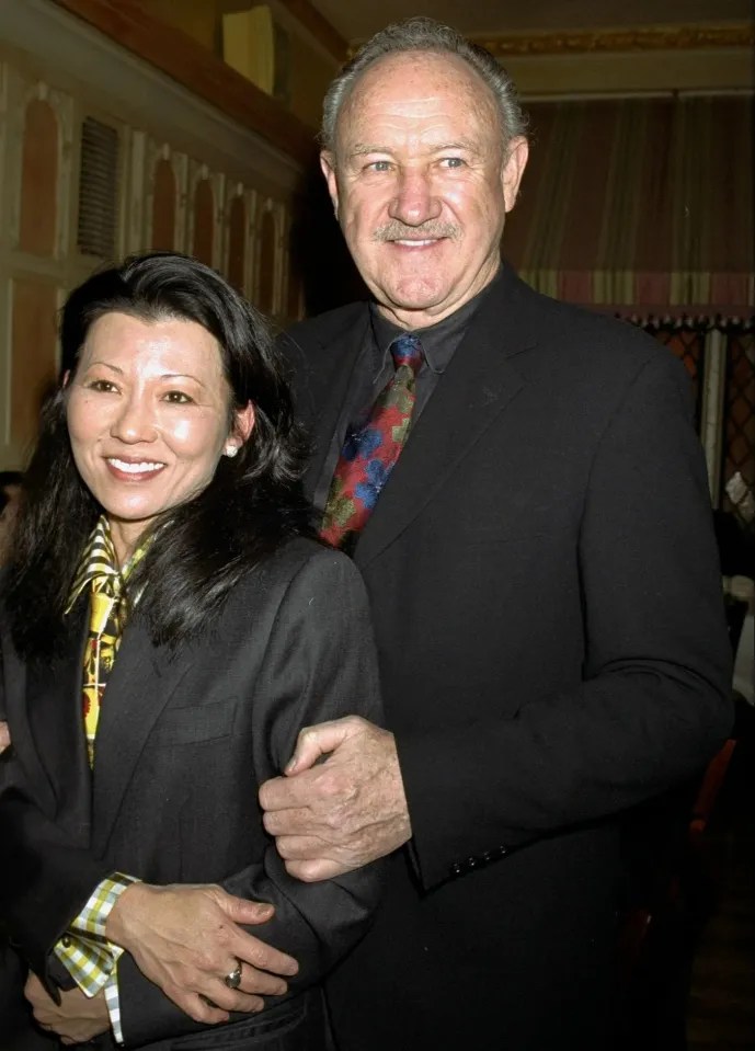 A man and woman in suits, arm in arm.