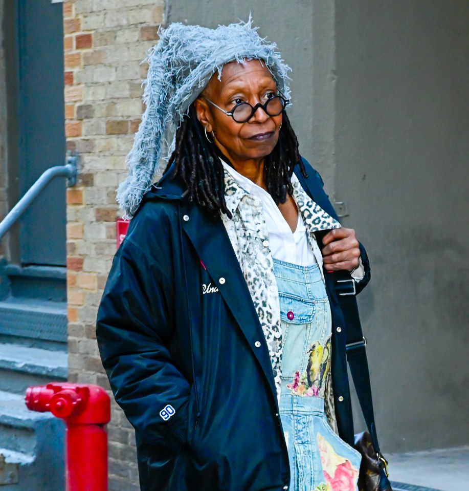 Whoopi Goldberg wearing a gray hat, glasses, and a dark jacket.