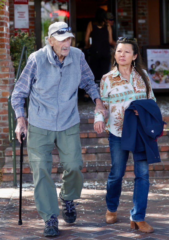 Gene Hackman and his wife walking together, he uses a cane.