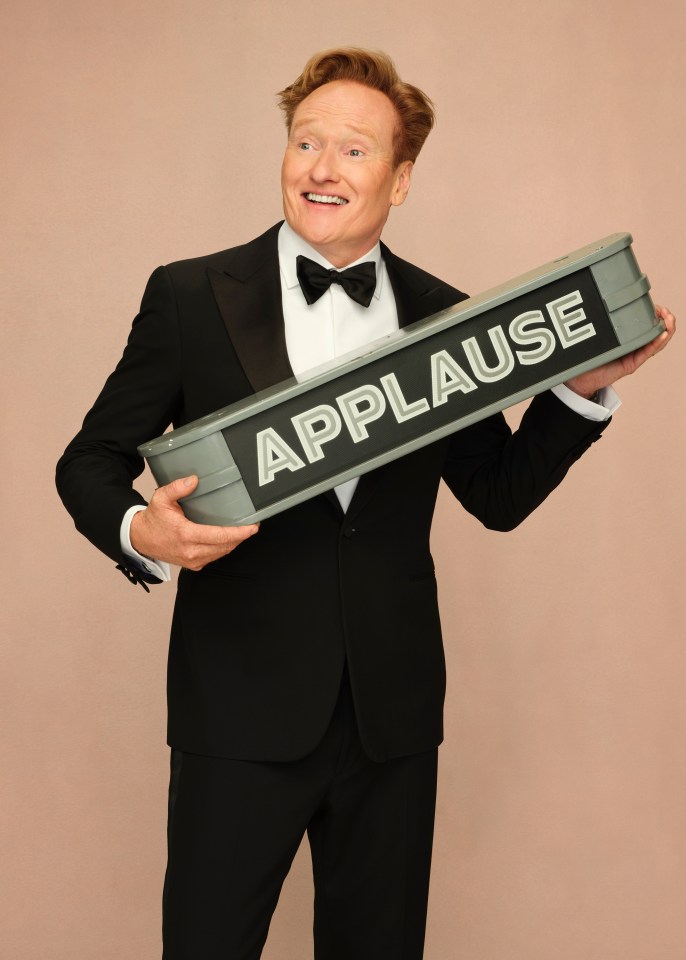 Conan O'Brien holding an applause sign at the Oscars.