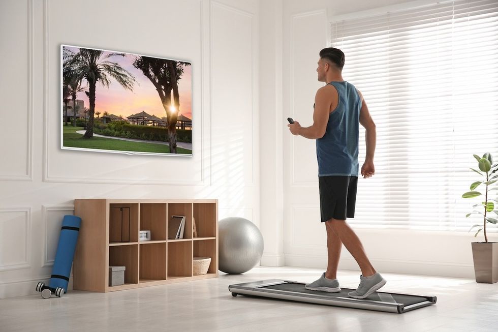 man using a walking pad while watching TV