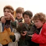 The Goonies cast looking at a treasure map.