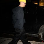 Justin Bieber walking near a car at night.