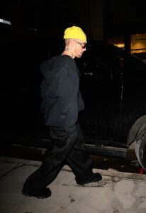 Justin Bieber walking near a car at night.