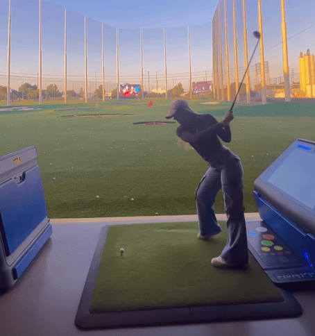 a woman is swinging a golf club at a golf ball