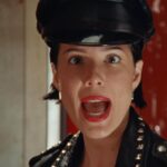 Halsey in a music video, wearing a leather cap and jacket.