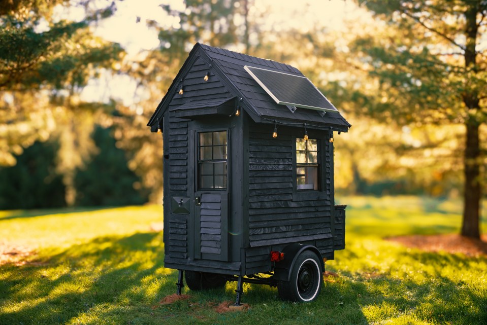 Small black house on wheels with solar panel.