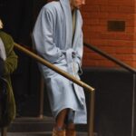 Justin Bieber in a light blue robe and brown slippers descending a staircase.