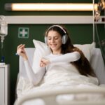 A hospital patient smiles as she listens to music in bed.