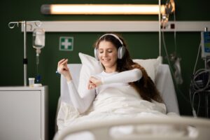 A hospital patient smiles as she listens to music in bed.