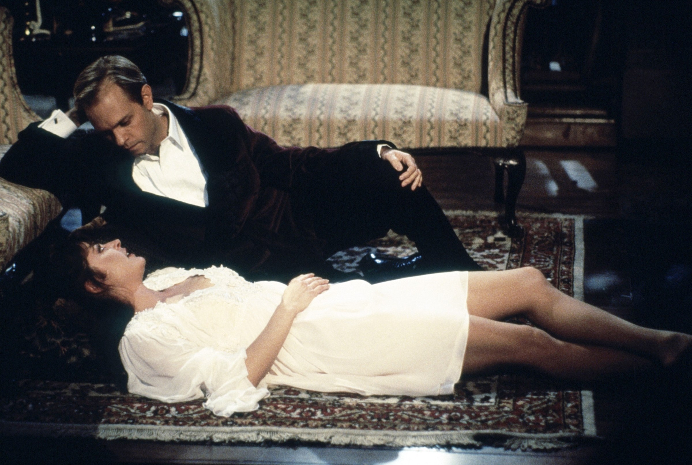 Niles Crane lounging on the floor, gazing down at Daphne Moon, who wears a white night gown. From Frasier