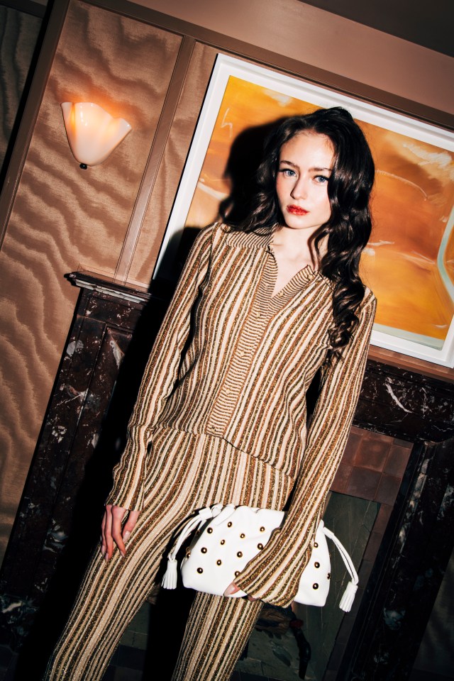 Leni Klum at a party in New York, wearing a striped outfit and holding a white clutch.