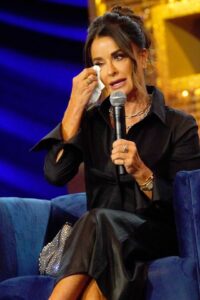 Kyle Richards wiping away tears while speaking into a microphone.