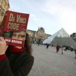 A "Da Vinci Code" fan holding a copy of the novel in front of the Louvre in 2005.