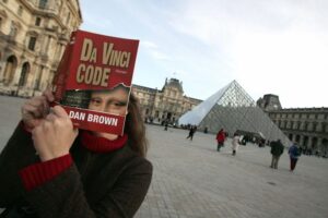 A "Da Vinci Code" fan holding a copy of the novel in front of the Louvre in 2005.