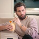 Scott Disick sitting on a couch holding a cocktail.