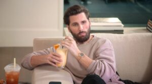 Scott Disick sitting on a couch holding a cocktail.