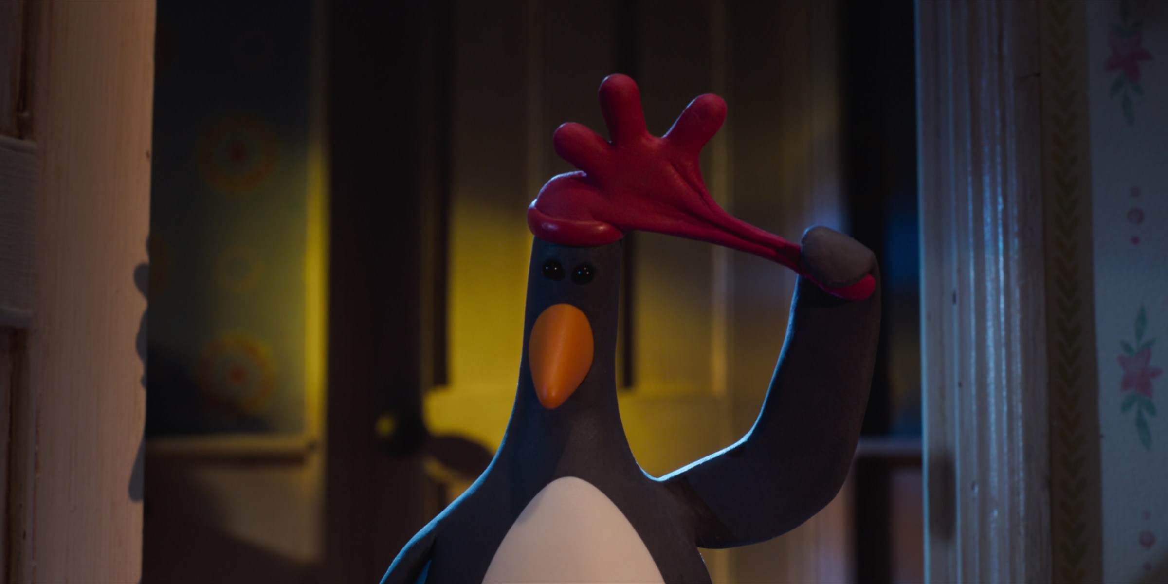 Feathers McGraw, a penguin, pulling off a red rubber glove hat. From Wallace & Gromit: Vengeance Most Fowl