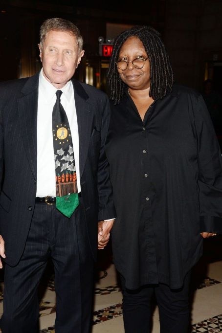 Whoopi Goldberg and her partner holding hands.