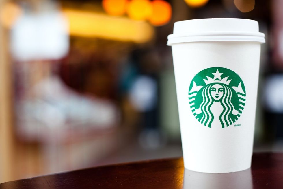 "Halifax, Nova Scotia, A!anada - September 18, 2011: A Grande Starbucks to go cup sitting on a table. Starbucks is a very popular International Coffeehouse franchise with over 15,000 locations in 50 countries"