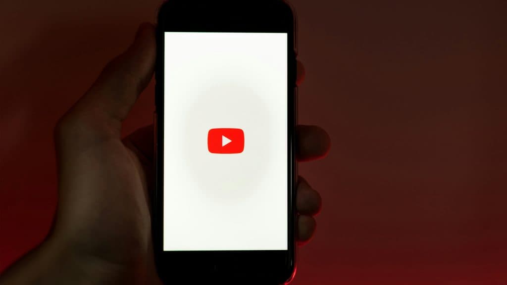 The YouTube logo on a smartphone being held in someone's hand.