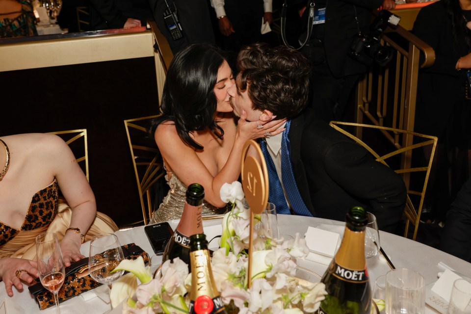 Kylie Jenner and Timothée Chalamet kissing at a table.