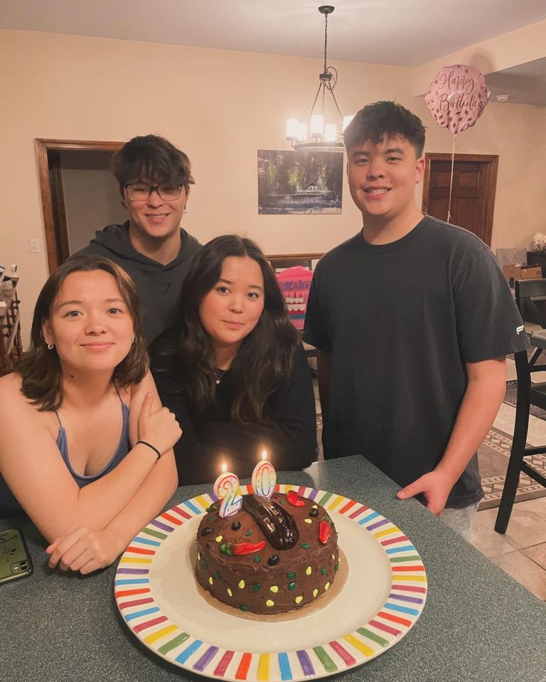 Four young adults celebrating a 20th birthday with a cake.