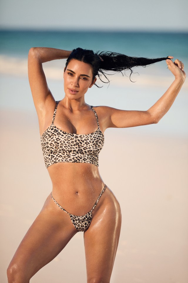 Kim Kardashian in a leopard-print Skims swimsuit on a beach.