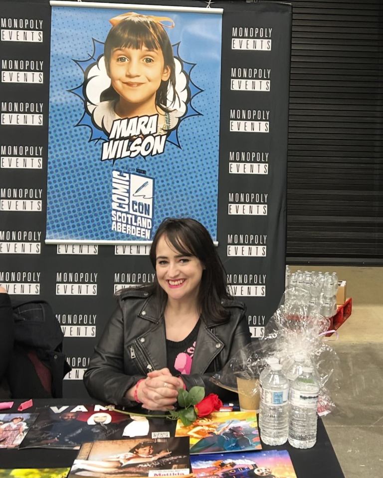 Mara Wilson, Matilda actress, at a Comic Con signing table.